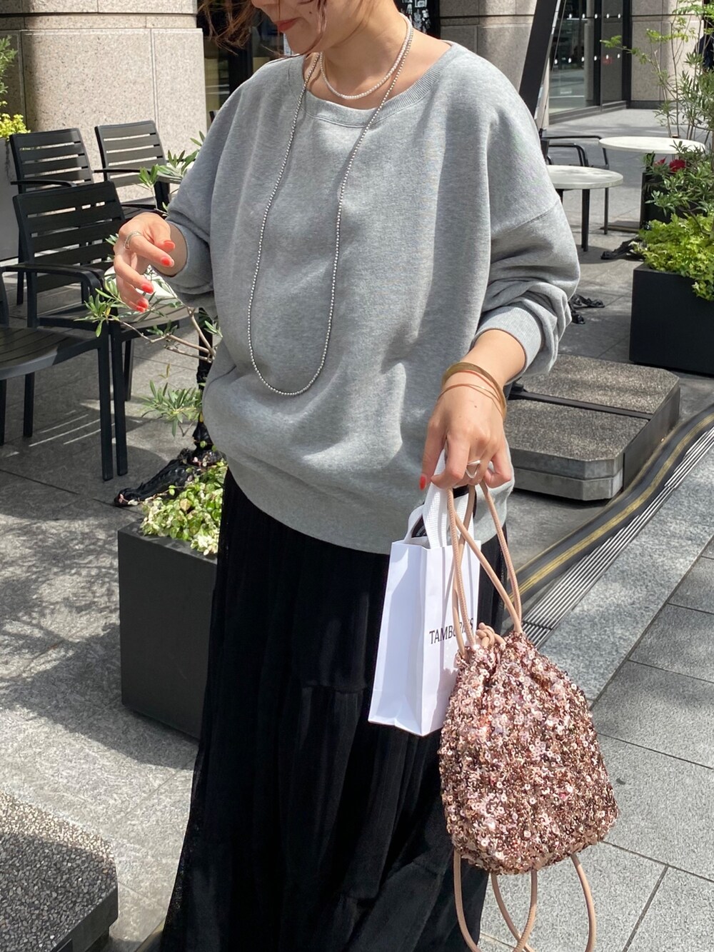 グレー系のスウェット、ブラック系のスカート、ピンク系のハンドバッグを着用したレディースの秋コーディネートの3枚目の写真