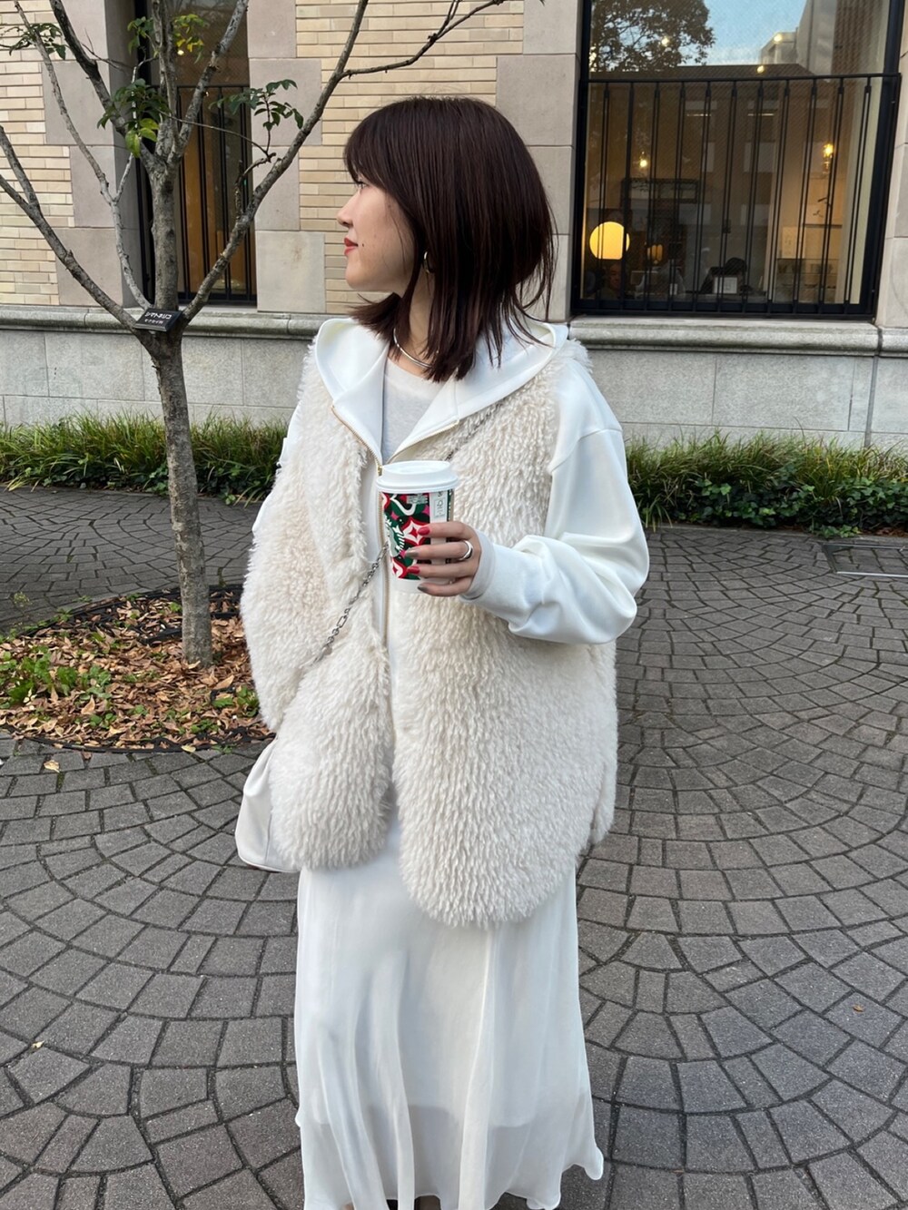 ホワイト系のベスト、ホワイト系のパーカー、ホワイト系のスカートを着用したレディースの冬コーディネートの3枚目の写真