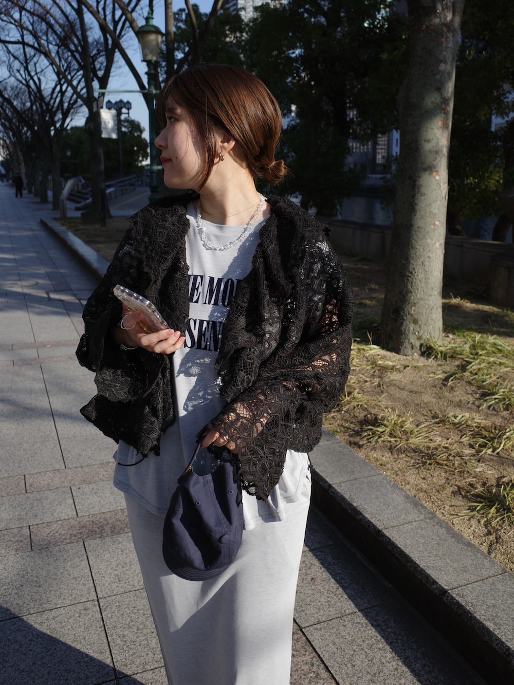 ブラック系のシャツ/ブラウス、グレー系のTシャツ/カットソー、グレー系のスカートを着用したレディースの春コーディネートの2枚目の写真