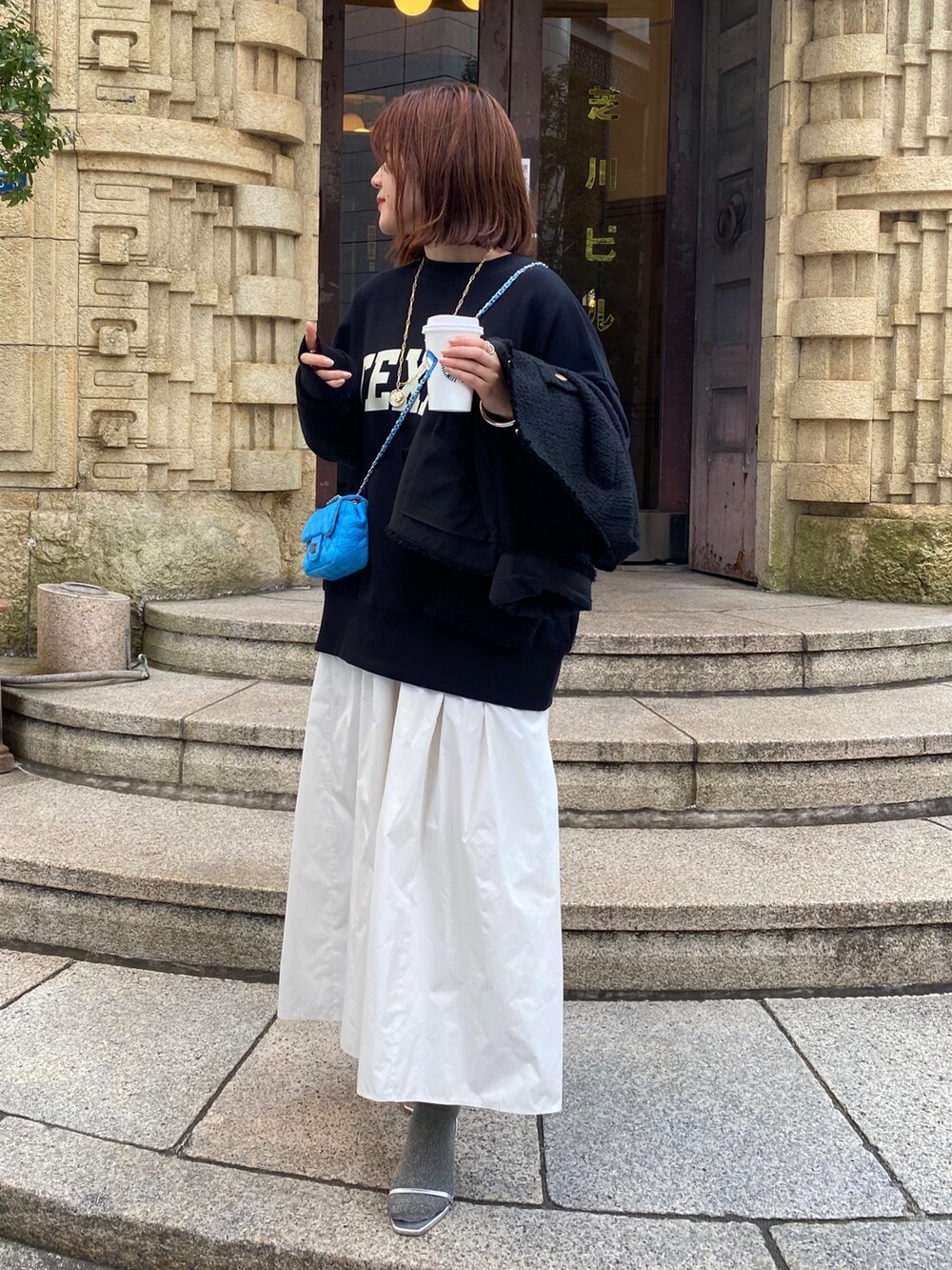 ブラック系のスウェット、ブラック系のノーカラージャケット、ホワイト系のスカートを着用したレディースの春コーディネートの4枚目の写真