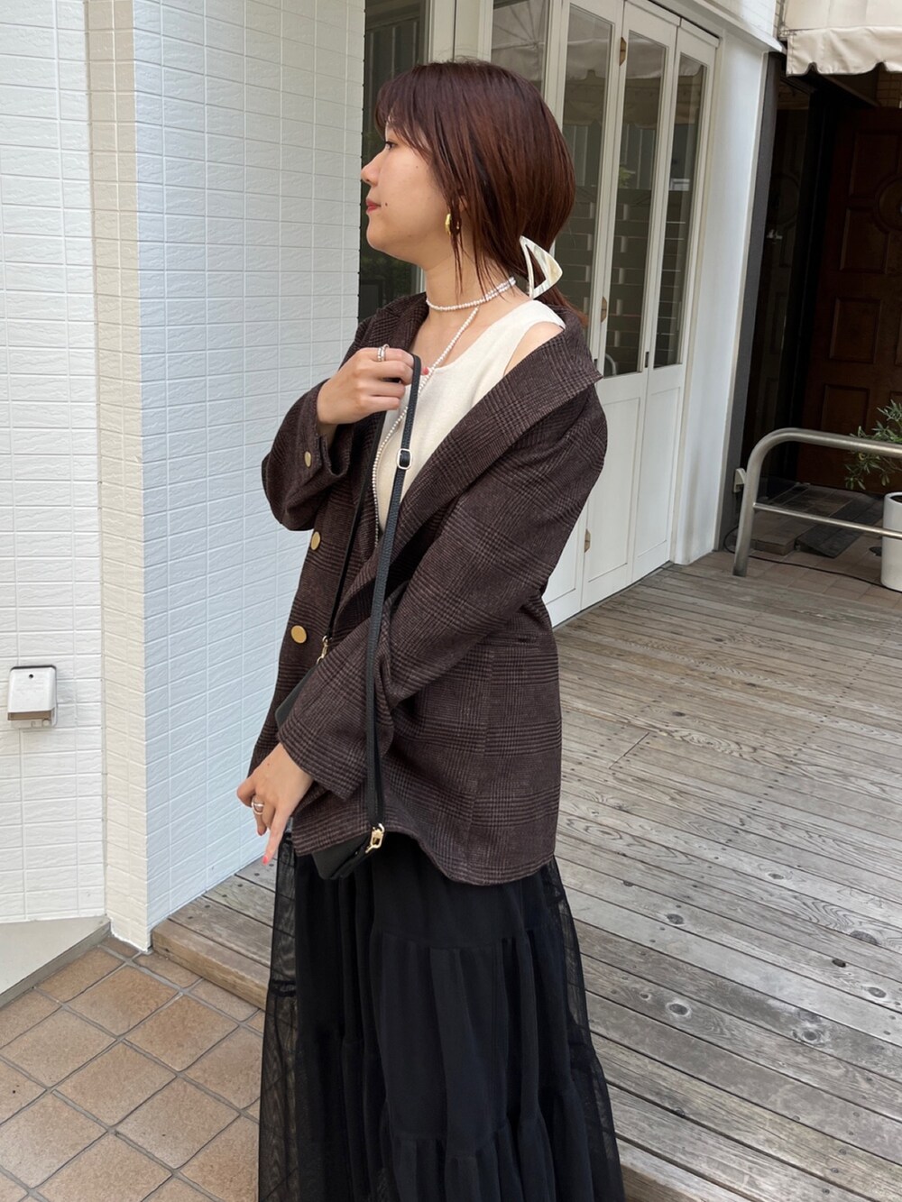 ブラウン系のテーラードジャケット、ブラック系のスカート、ブラック系のショルダーバッグを着用したレディースの秋コーディネートの7枚目の写真
