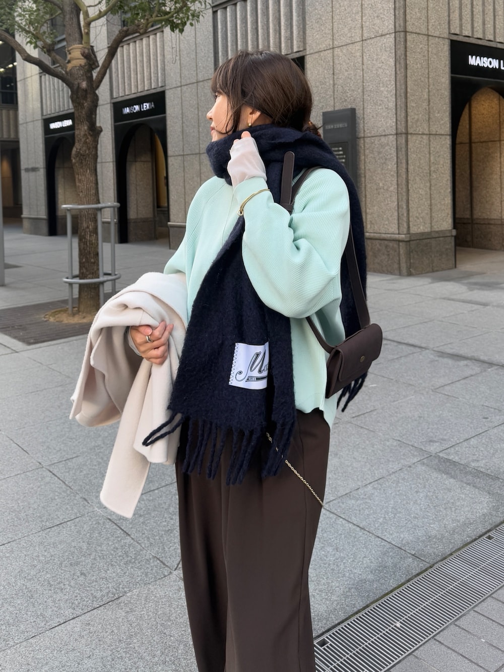 グリーン系のニット/セーター、ブラウン系のスラックス、グレー系のTシャツ/カットソーを着用したレディースの冬コーディネートの7枚目の写真