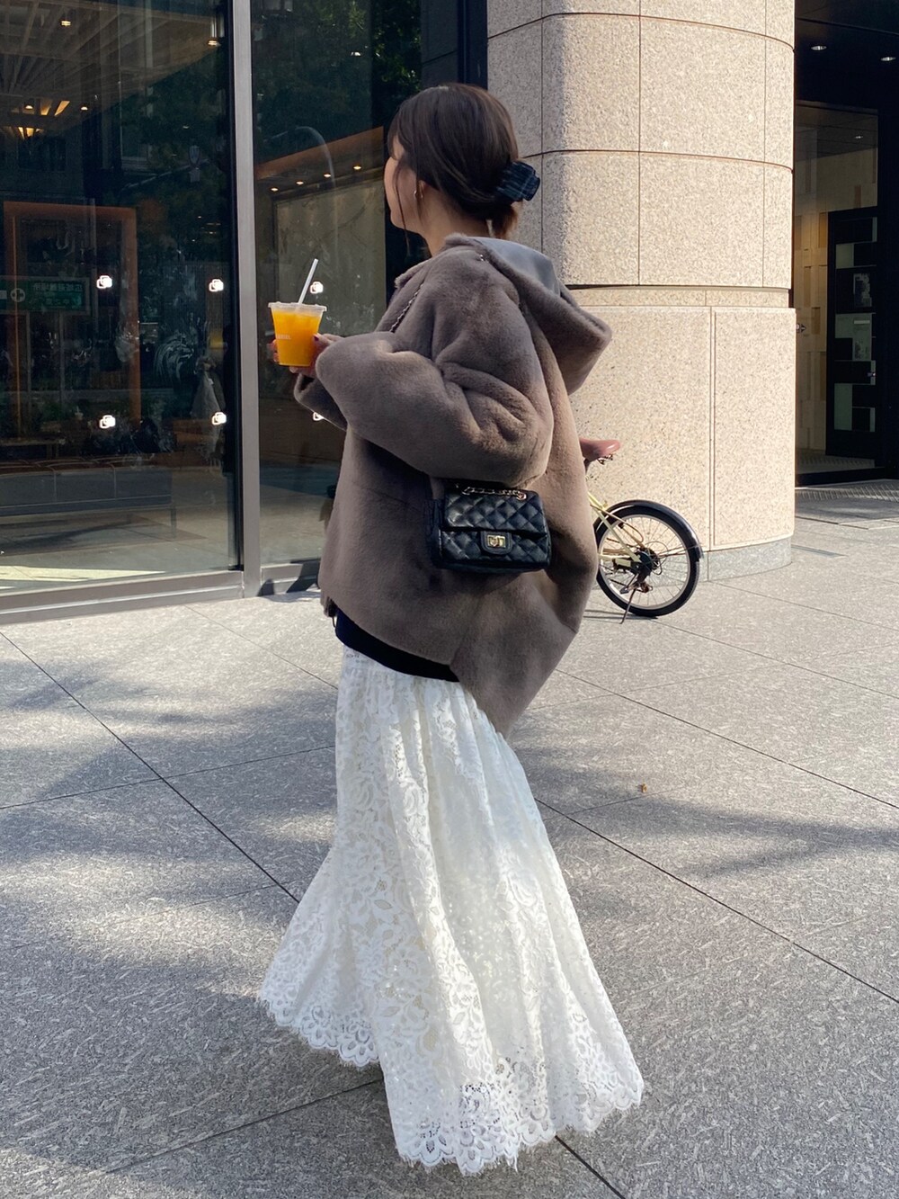 グレー系のムートンコート、ブルー系のニット/セーター、ホワイト系のスカートを着用したレディースの冬コーディネートの7枚目の写真