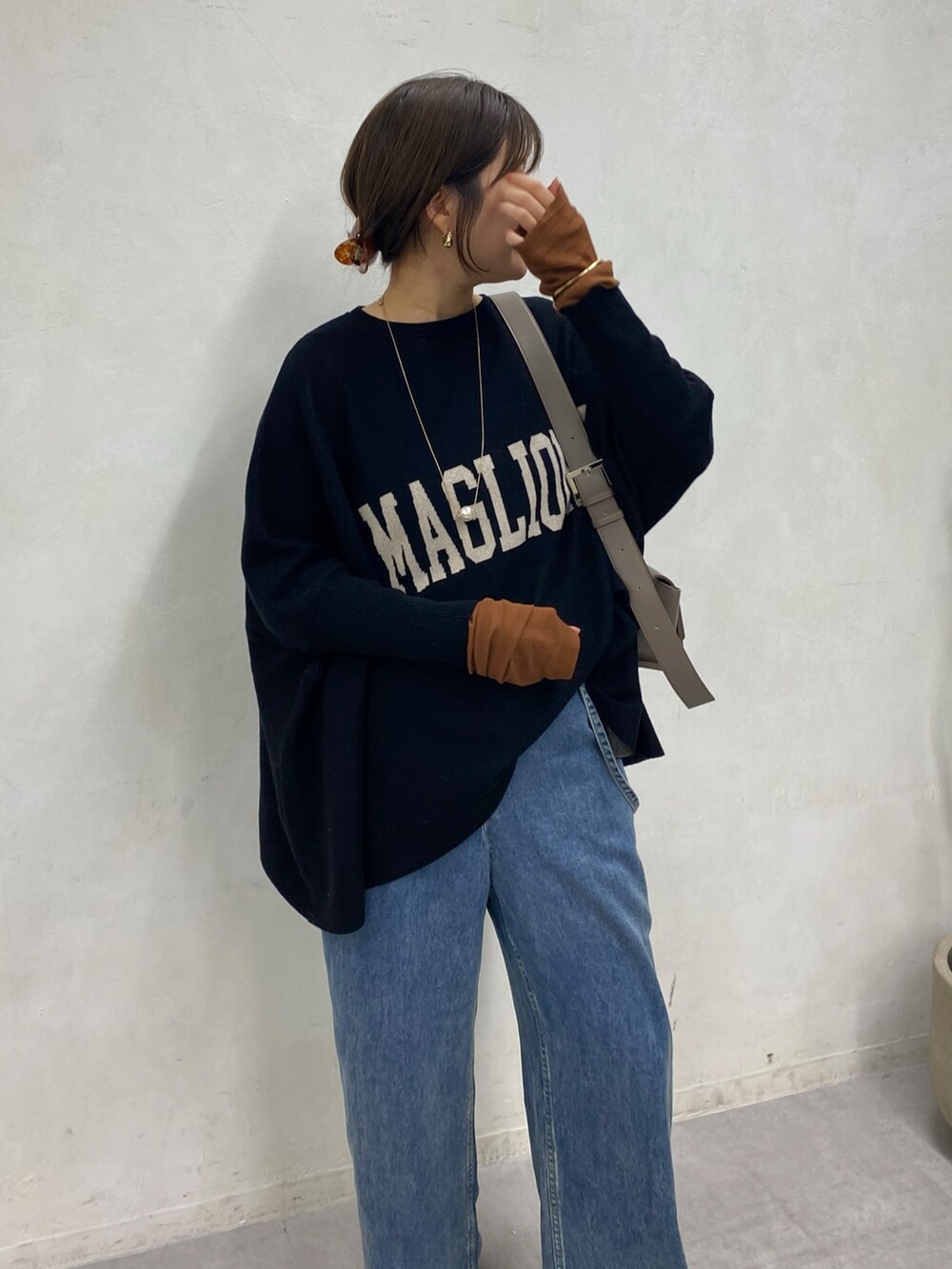 ブラック系のニット/セーター、ブルー系のデニムパンツ、ブラウン系のTシャツ/カットソーを着用したレディースの冬コーディネートの4枚目の写真