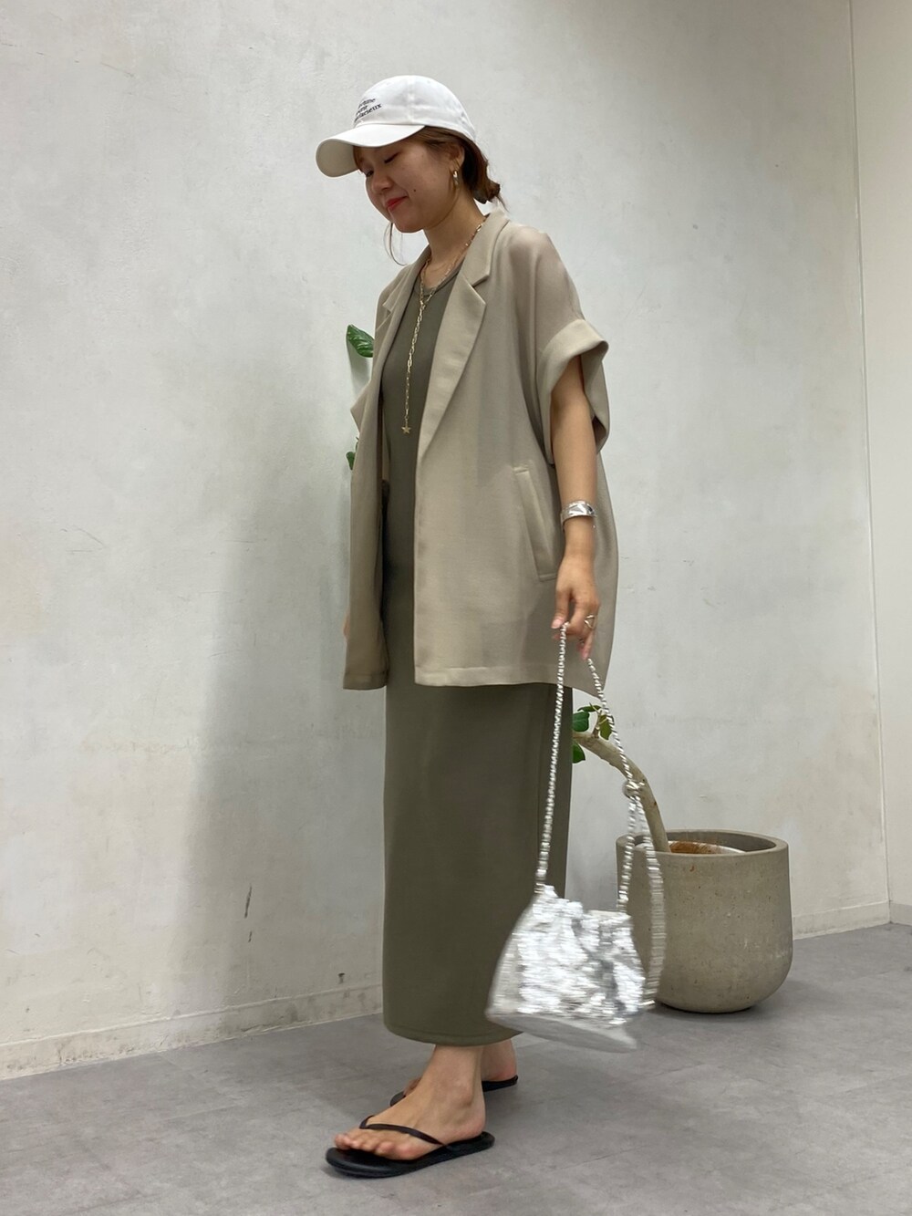 ベージュ系のテーラードジャケット、グリーン系のワンピース、シルバー系のショルダーバッグを着用したレディースの春コーディネートの4枚目の写真