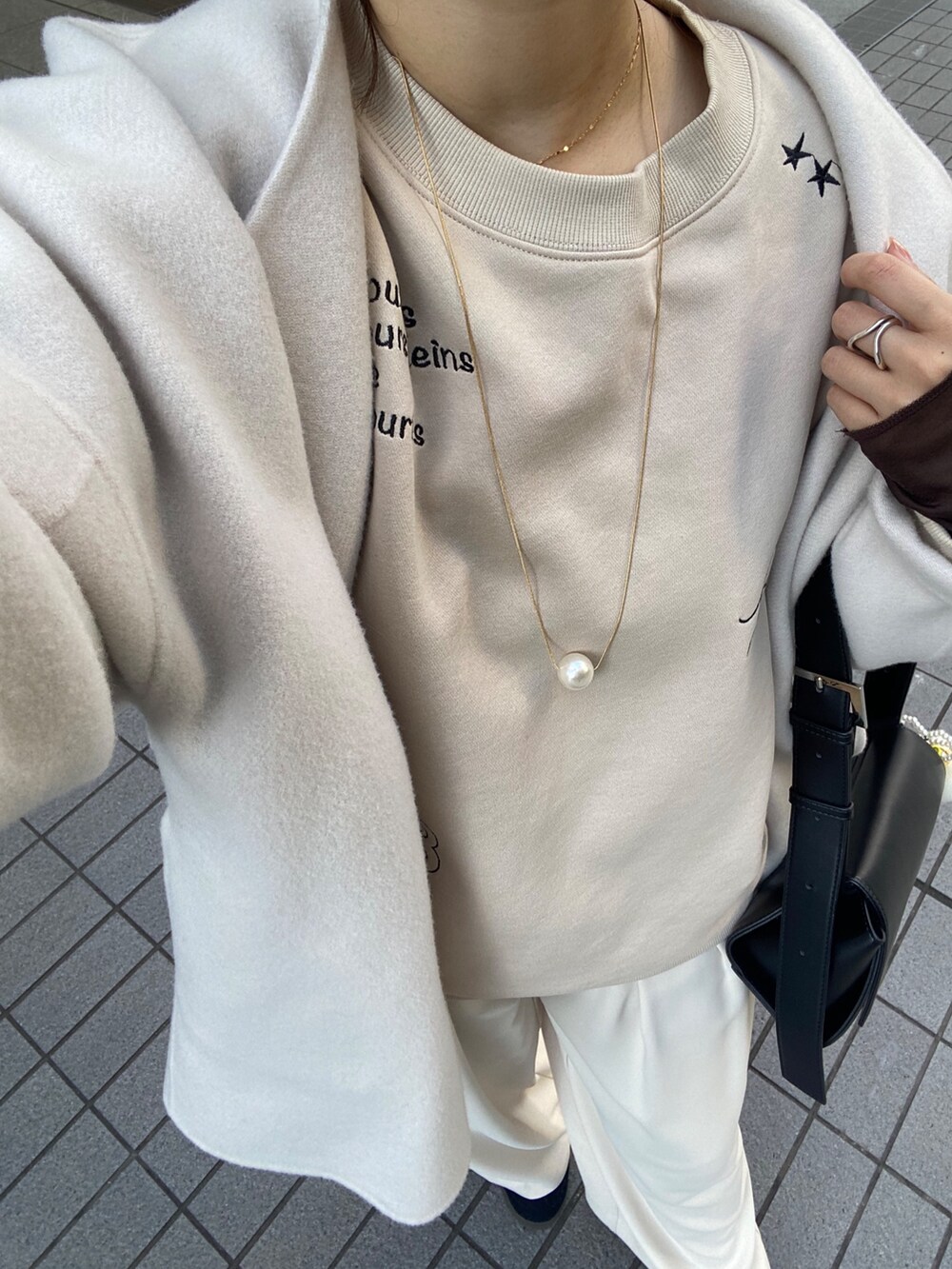 ホワイト系のその他アウター、ベージュ系のスラックス、ブラック系のショルダーバッグを着用したレディースの秋コーディネートの2枚目の写真