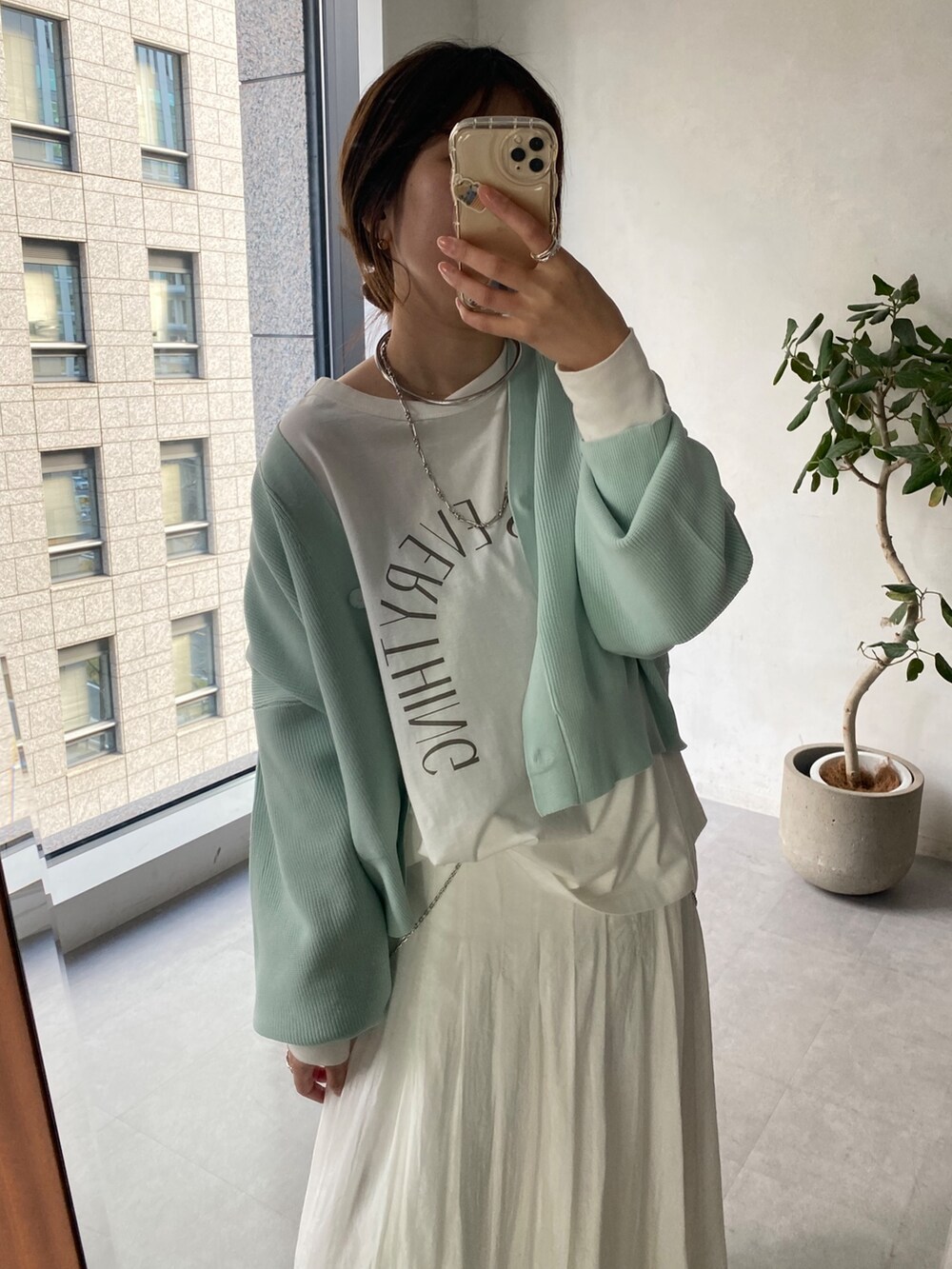 グリーン系のカーディガン/ボレロ、ホワイト系のスカートを着用したレディースの冬コーディネートの4枚目の写真