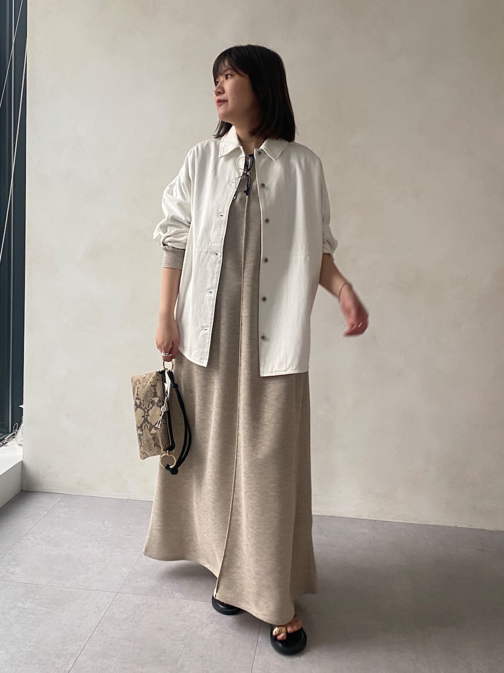 ホワイト系のシャツ/ブラウス、ベージュ系のワンピース、ブラック系のサンダルを着用したレディースの春コーディネートの2枚目の写真