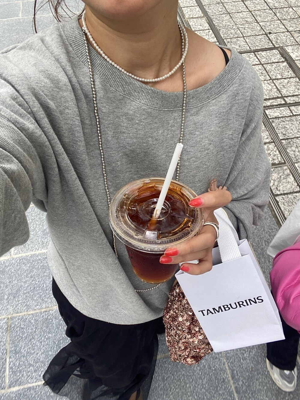 グレー系のスウェット、ブラック系のスカート、ピンク系のハンドバッグを着用したレディースの秋コーディネートの9枚目の写真