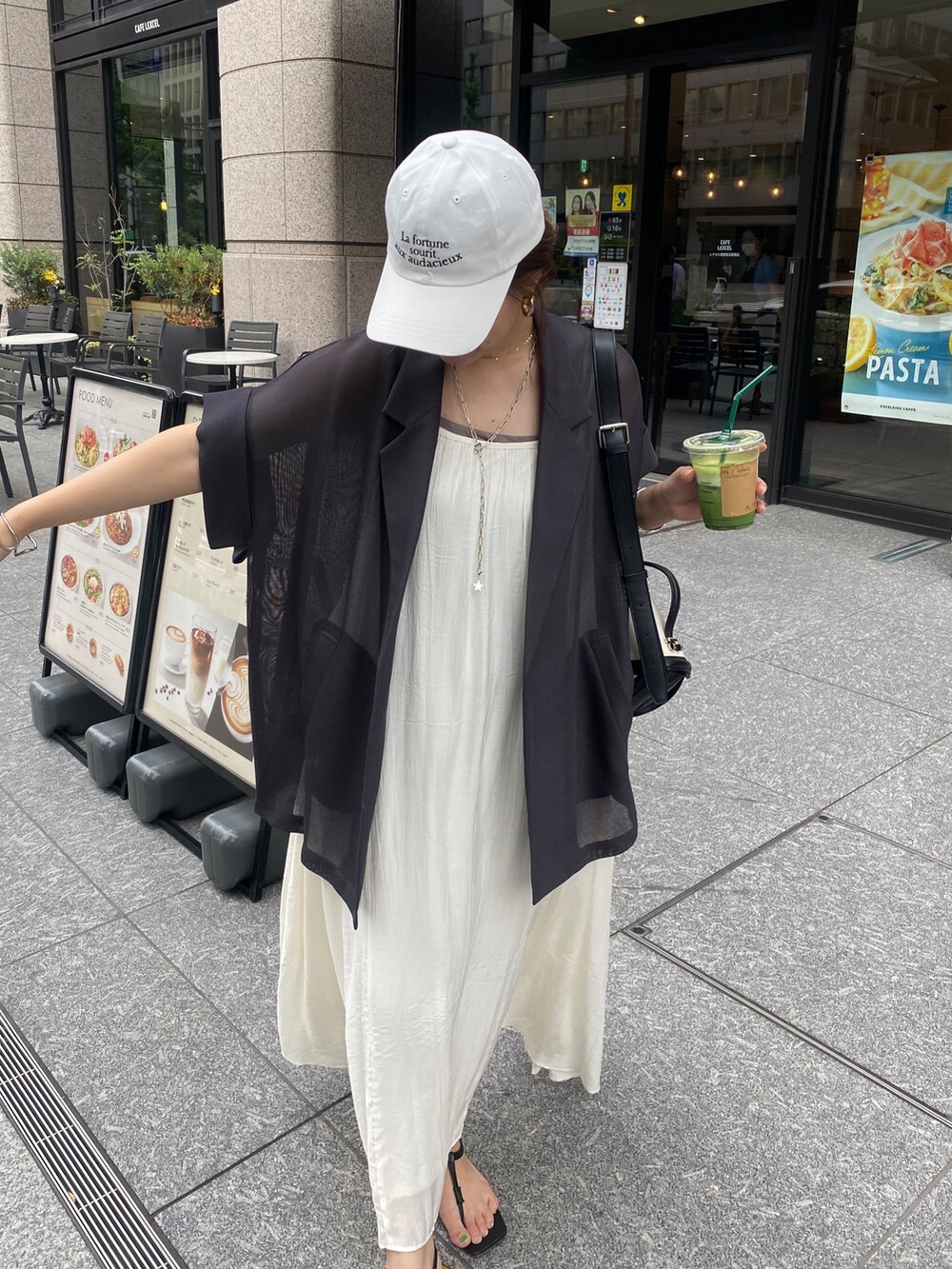 グレー系のテーラードジャケット、ホワイト系のワンピース、ホワイト系のキャップを着用したレディースの夏コーディネートの2枚目の写真