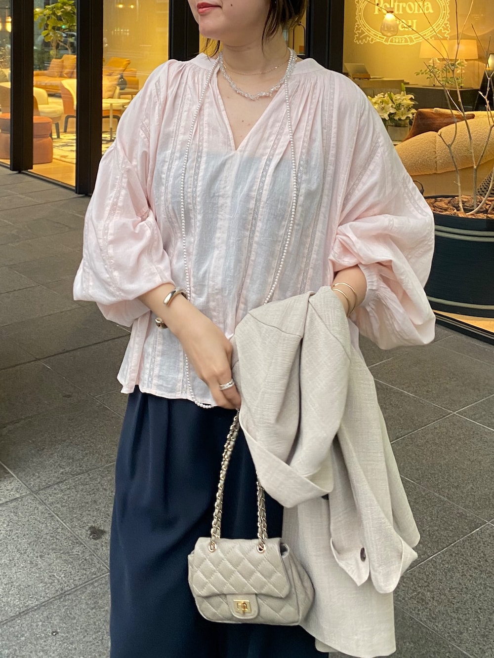 ピンク系のシャツ/ブラウス、ブルー系のスラックス、その他のネックレスを着用したレディースの春コーディネートの2枚目の写真