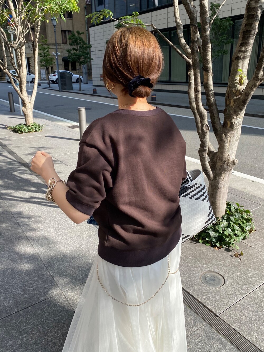 ブラウン系のスウェット、ホワイト系のスカート、ブルー系のデニムジャケットを着用したレディースの春コーディネートの7枚目の写真