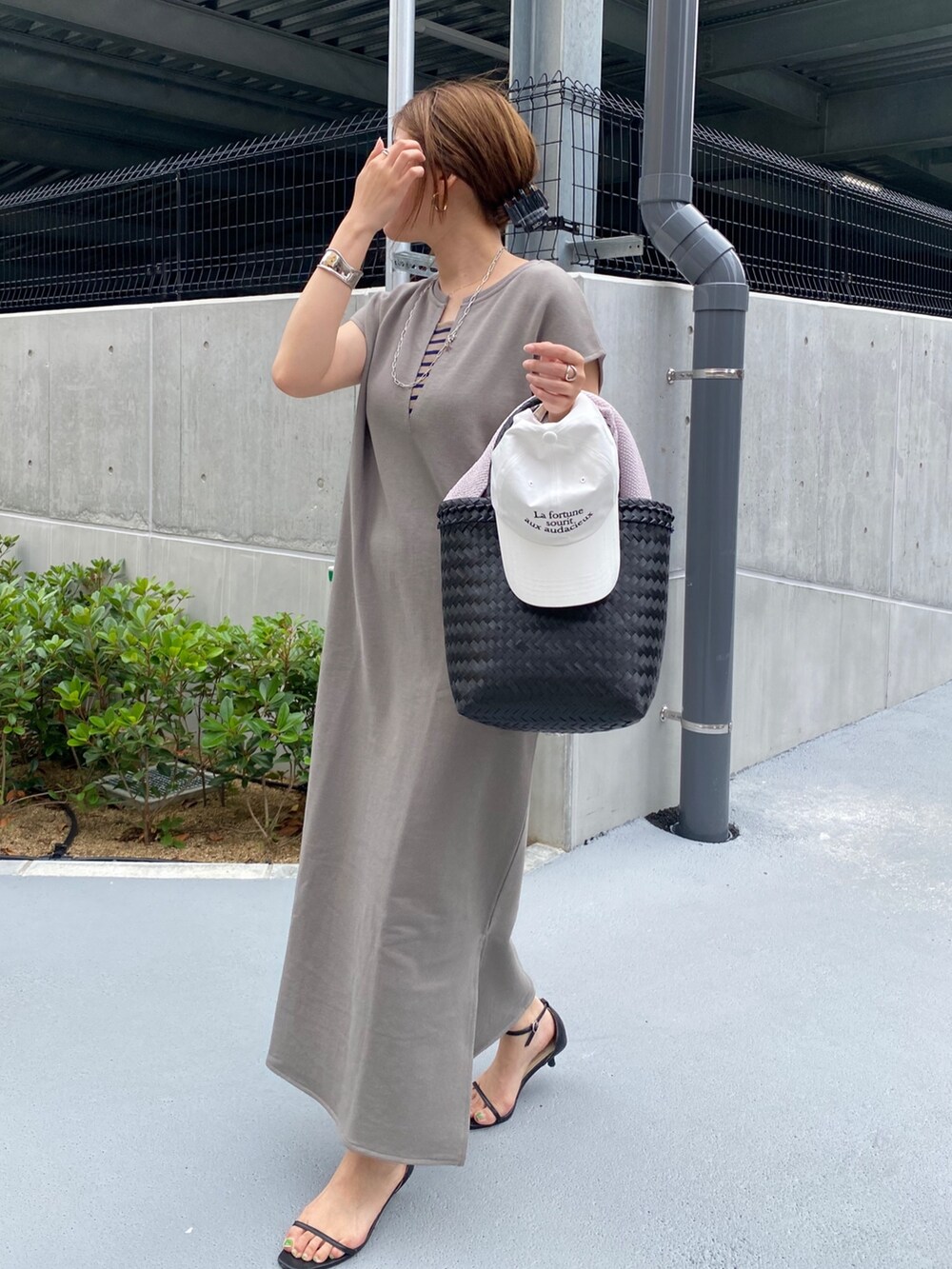 ホワイト系のワンピース、ブラック系のかごバッグ、ブラック系のニット/セーターを着用したレディースの春コーディネートの7枚目の写真