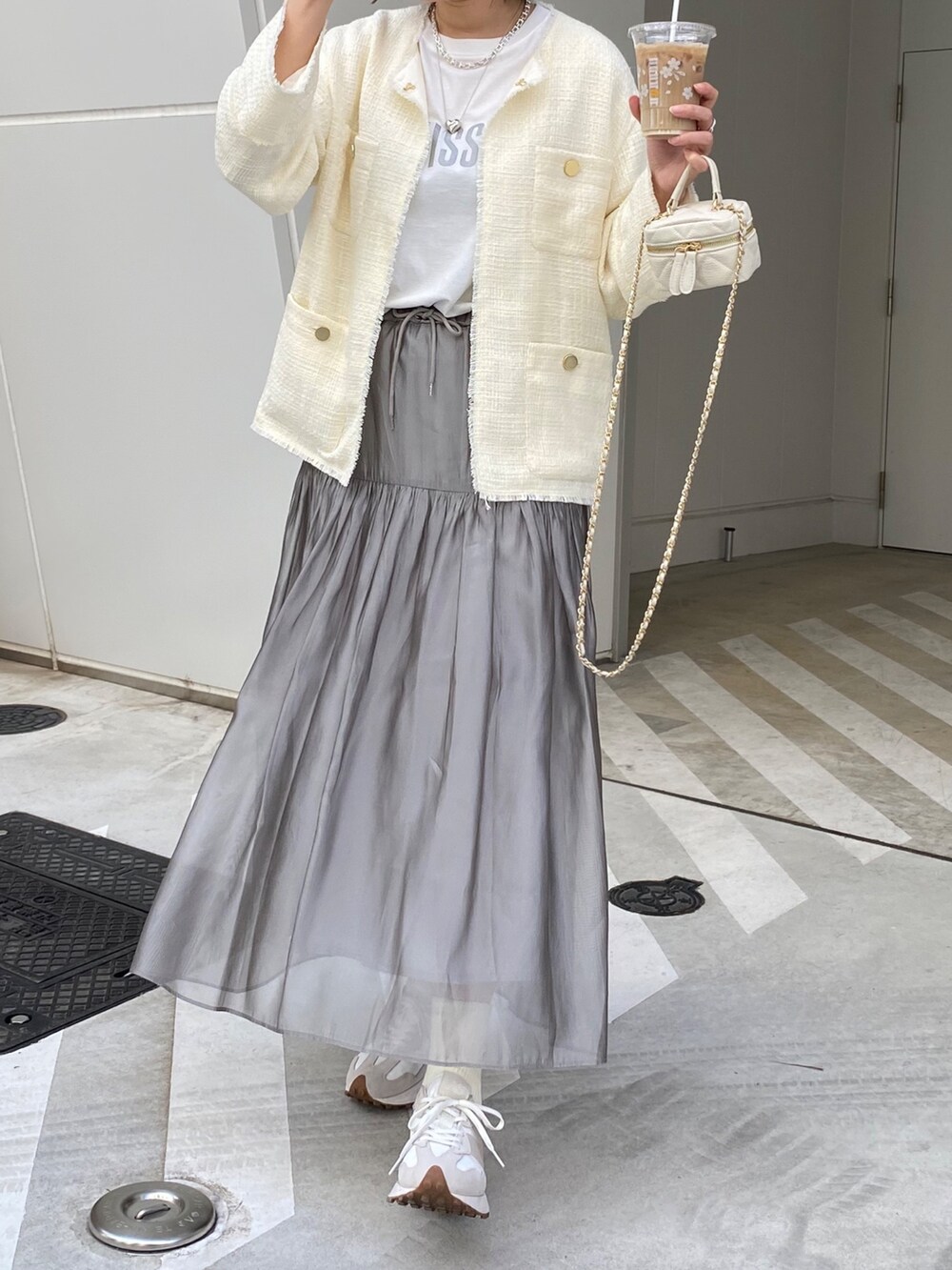 ホワイト系のノーカラージャケット、ホワイト系のスニーカー、ブラック系のショルダーバッグを着用したレディースの春コーディネートの6枚目の写真