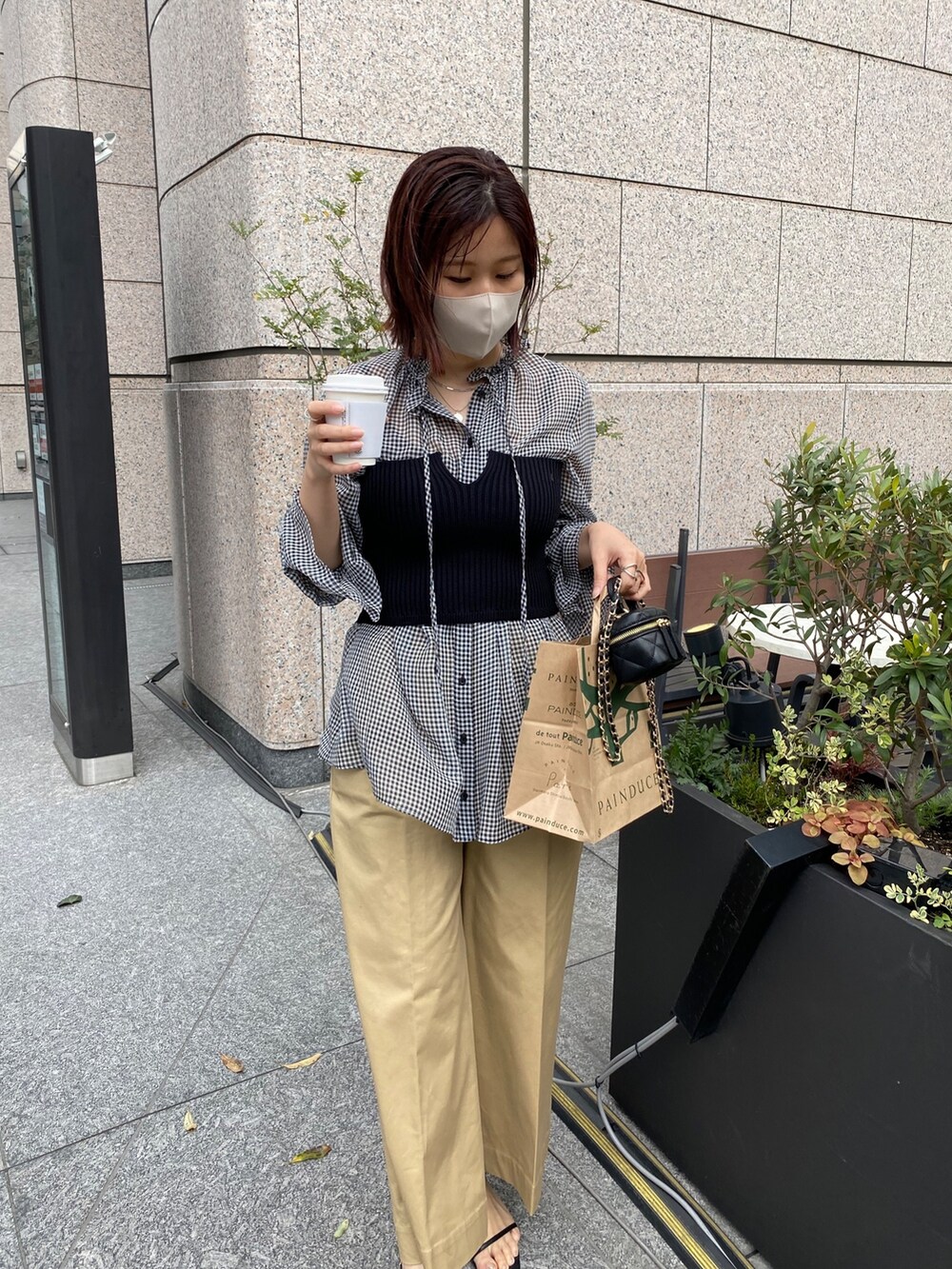 ブラック系のニット/セーター、ブラック系のシャツ/ブラウス、ベージュ系のチノパンツを着用したレディースの春コーディネートの3枚目の写真