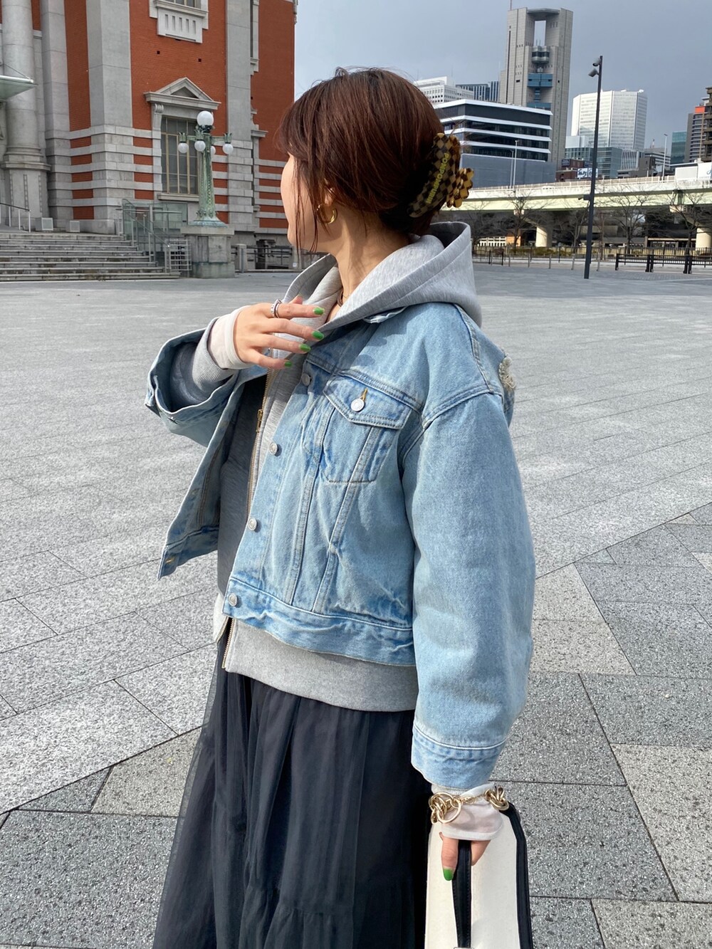 ブルー系のデニムジャケット、グレー系のワンピース、グレー系のパーカーを着用したレディースの春コーディネートの3枚目の写真