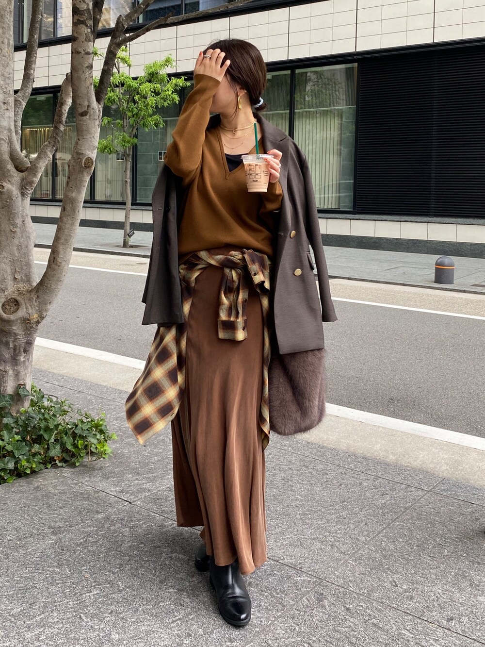 イエロー系のニット/セーター、ブラウン系のスカート、オレンジ系のシャツ/ブラウスを着用したレディースの冬コーディネートの5枚目の写真