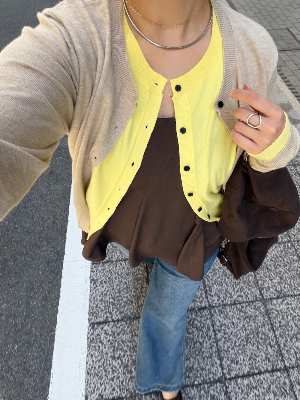 ベージュ系のカーディガン/ボレロ、ブラウン系のキャミソール、ブルー系のデニムパンツを着用したレディースの秋コーディネートの2枚目の写真