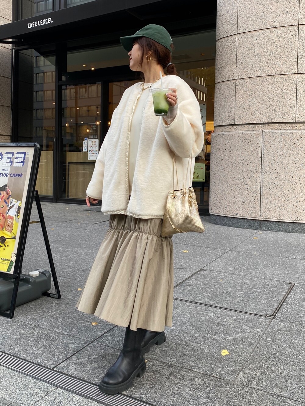 ホワイト系のダウンジャケット/コート、ゴールド系のショルダーバッグ、ホワイト系のワンピースを着用したレディースの冬コーディネートの3枚目の写真