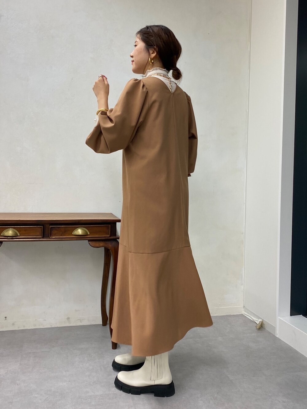 ベージュ系のワンピース、ホワイト系のTシャツ/カットソー、ホワイト系のブーツを着用したレディースの秋コーディネートの2枚目の写真