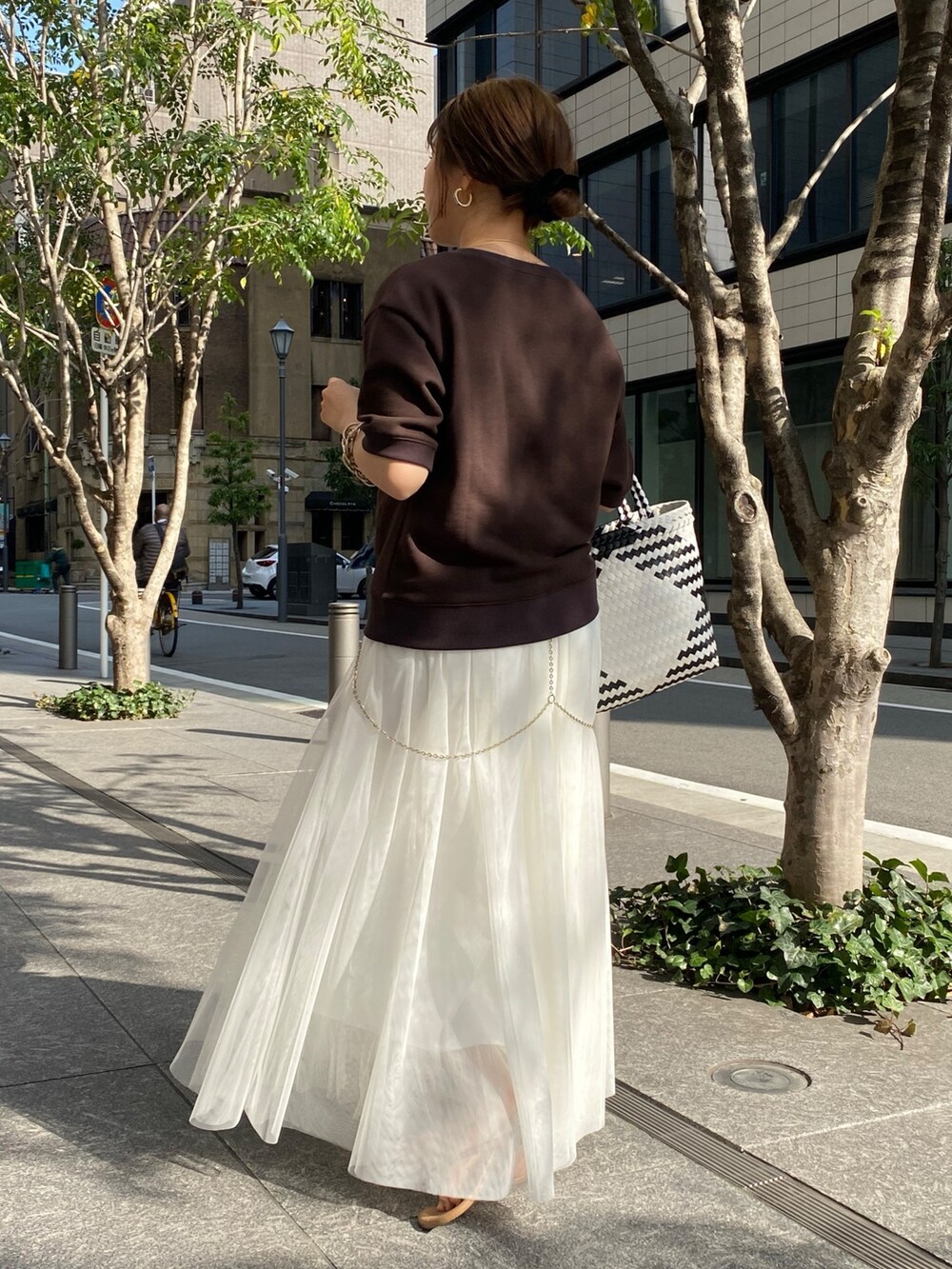 ブラウン系のスウェット、ホワイト系のスカート、ブルー系のデニムジャケットを着用したレディースの春コーディネートの8枚目の写真