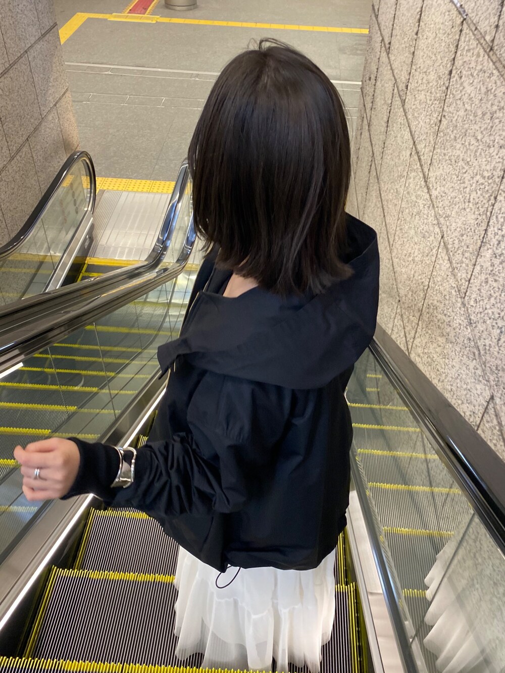 ブラック系のその他アウター、ホワイト系のスカート、イエロー系のショルダーバッグを着用したレディースの春コーディネートの3枚目の写真