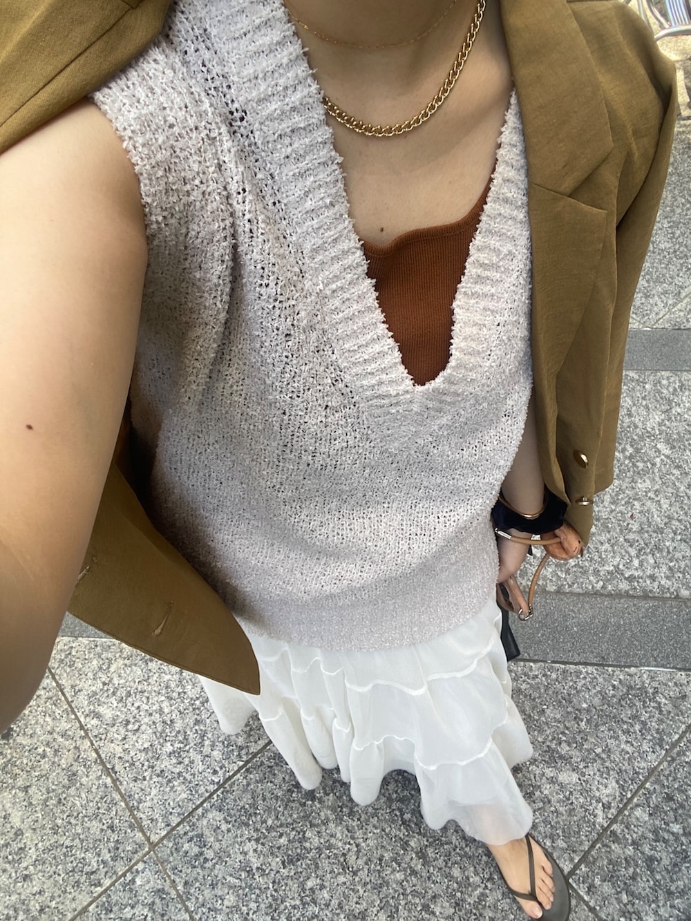 イエロー系のテーラードジャケット、ベージュ系のニット/セーター、ブラウン系のタンクトップを着用したレディースの夏コーディネートの8枚目の写真