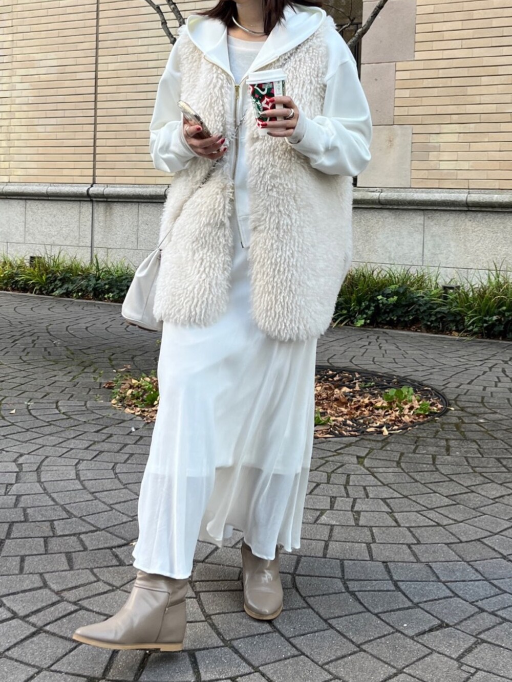 ホワイト系のベスト、ホワイト系のパーカー、ホワイト系のスカートを着用したレディースの冬コーディネートの10枚目の写真