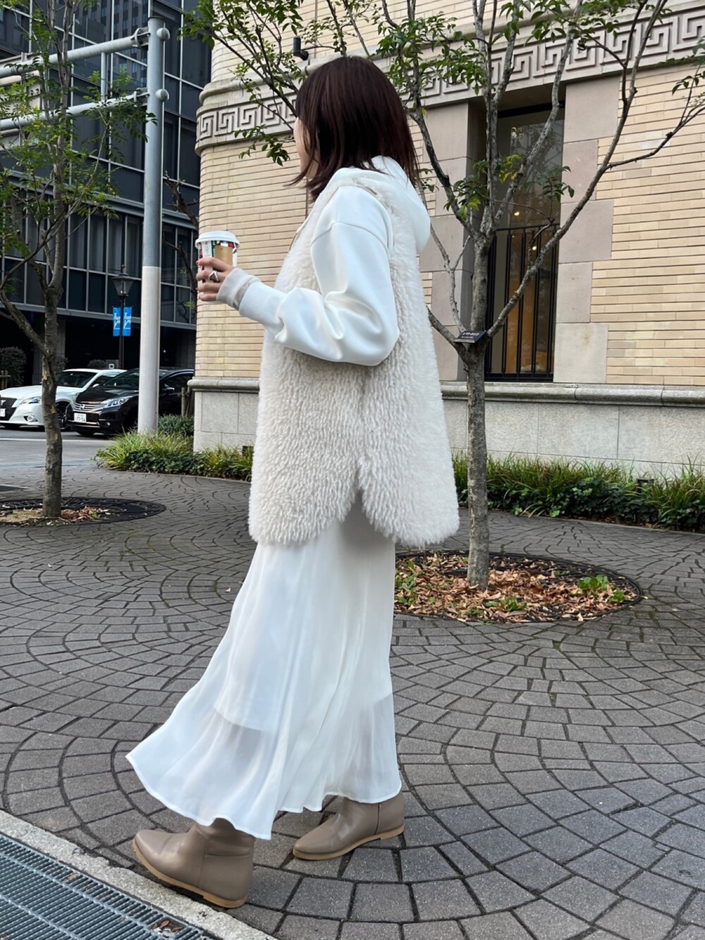ホワイト系のベスト、ホワイト系のパーカー、ホワイト系のスカートを着用したレディースの冬コーディネートの9枚目の写真