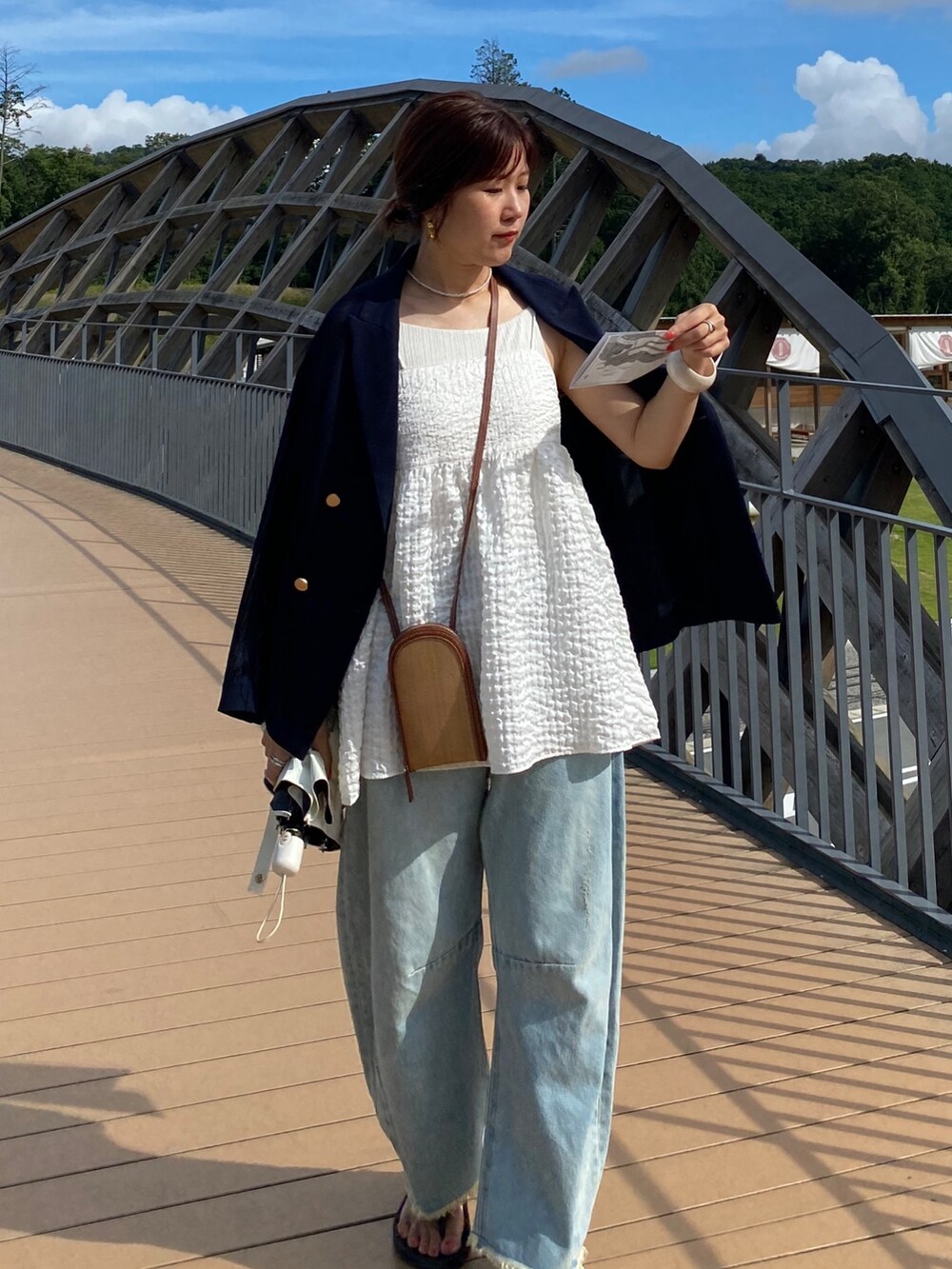 ブルー系のテーラードジャケット、ホワイト系のキャミソール、ブルー系のデニムパンツを着用したレディースの夏コーディネートの5枚目の写真