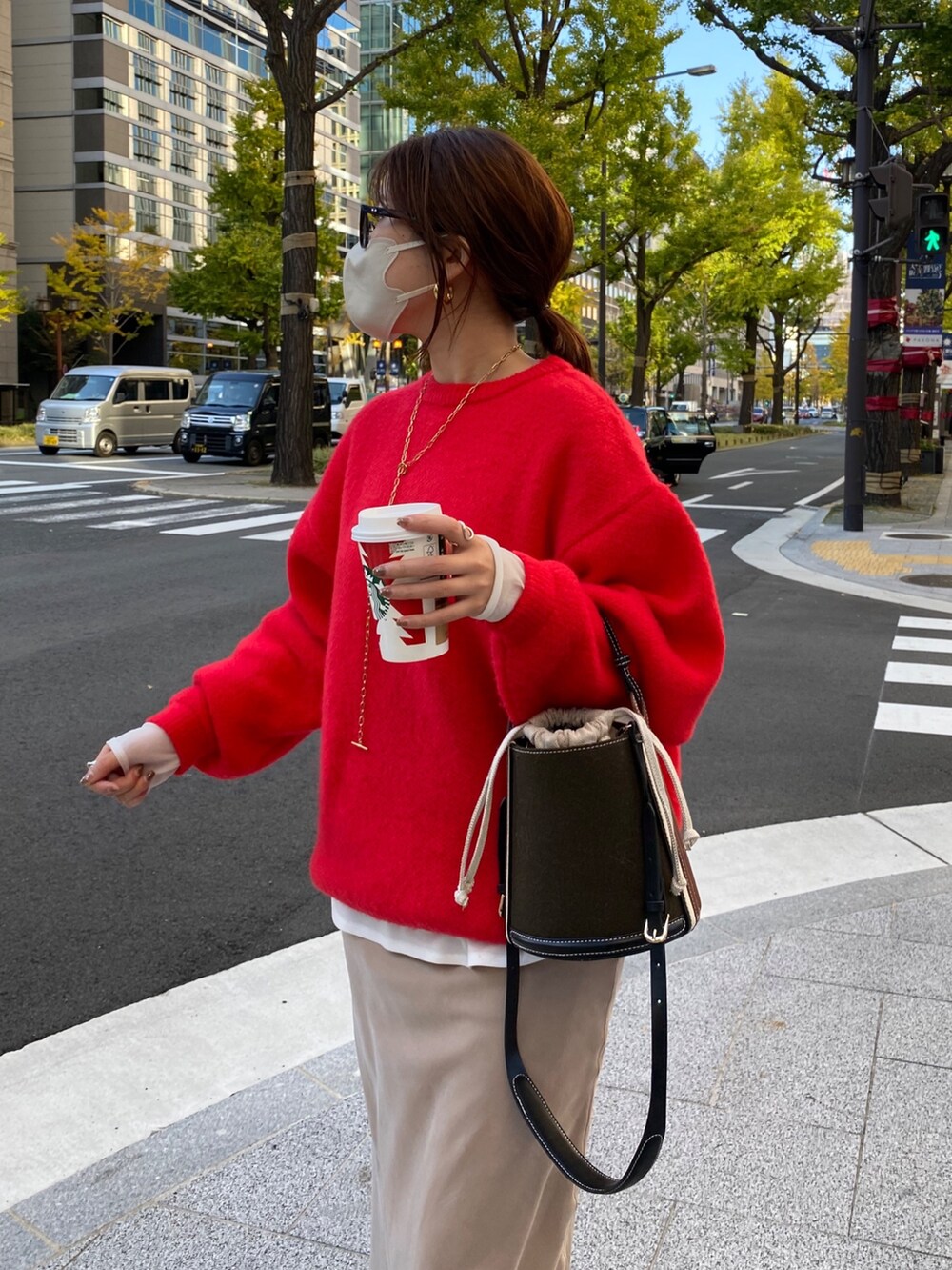 レッド系のニット/セーター、ホワイト系のTシャツ/カットソー、ベージュ系のスカートを着用したレディースの秋コーディネートの4枚目の写真