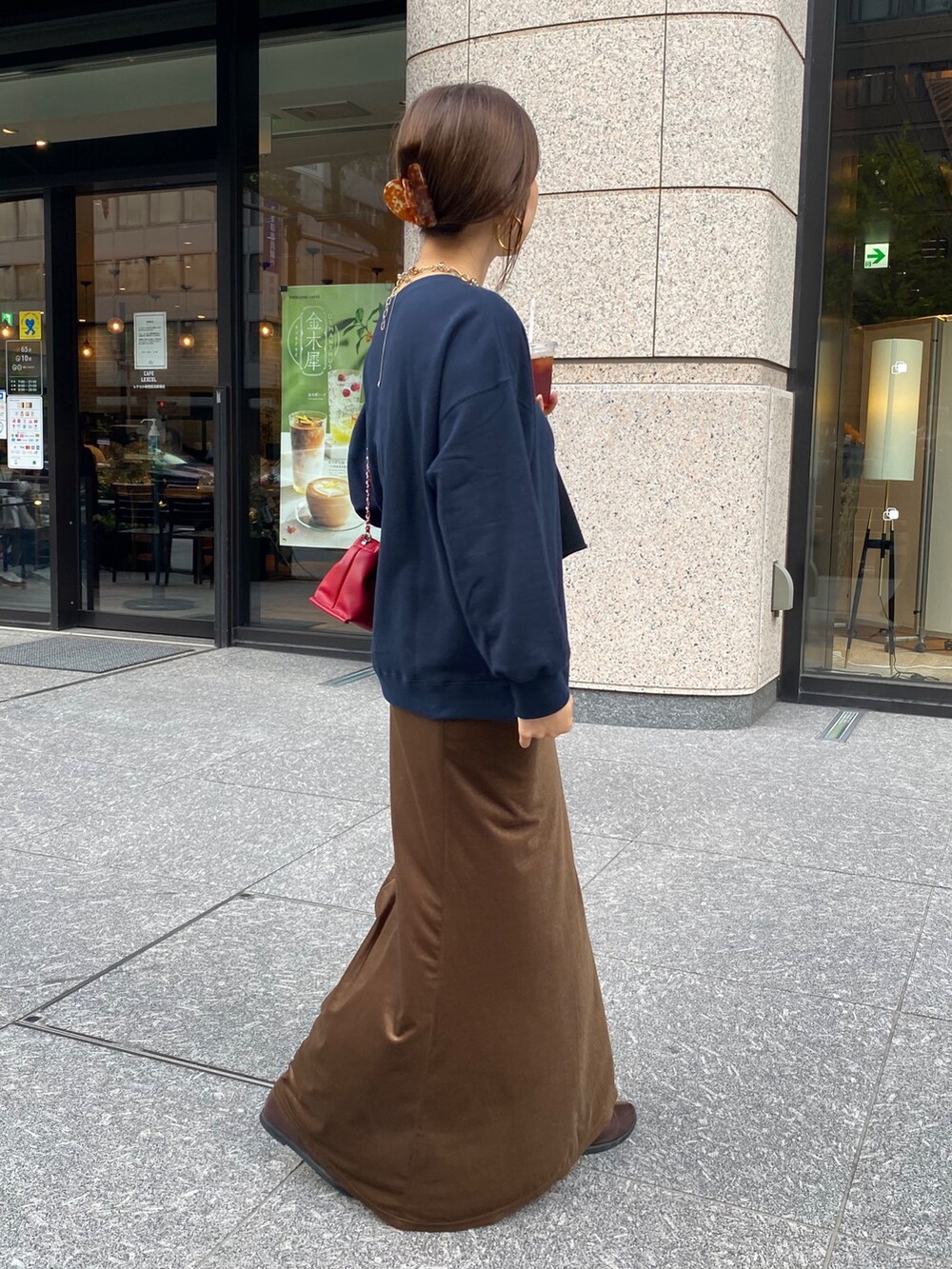 ブルー系のスウェット、ブラウン系のブーツ、レッド系のショルダーバッグを着用したレディースの秋コーディネートの4枚目の写真