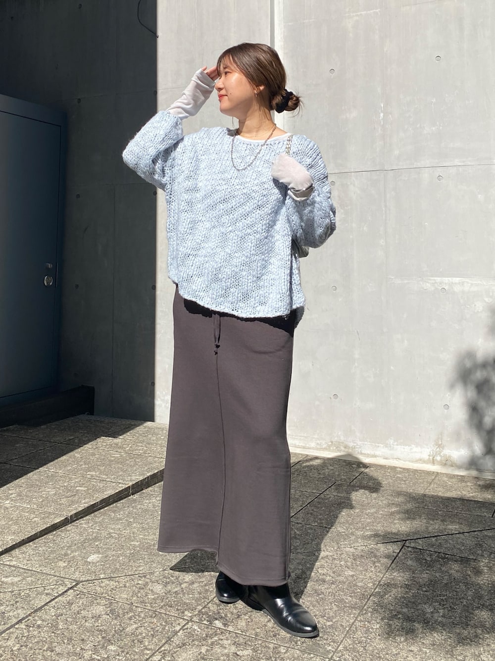 ブルー系のニット/セーター、ブルー系のTシャツ/カットソー、グレー系のムートンコートを着用したレディースの冬コーディネートの2枚目の写真