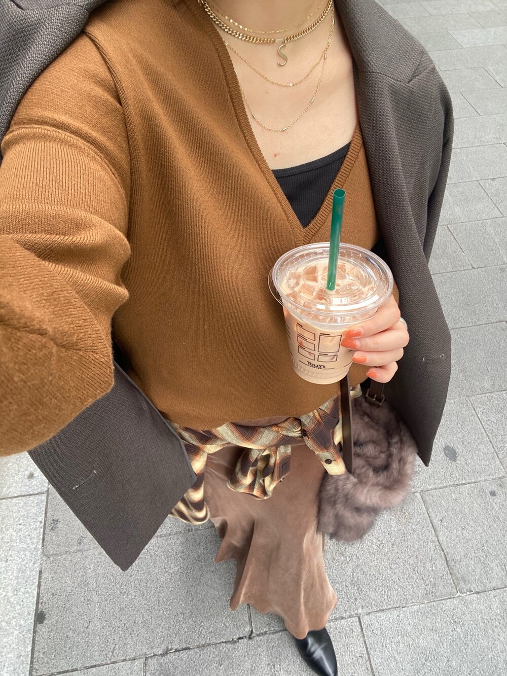 イエロー系のニット/セーター、ブラウン系のスカート、オレンジ系のシャツ/ブラウスを着用したレディースの冬コーディネートの10枚目の写真