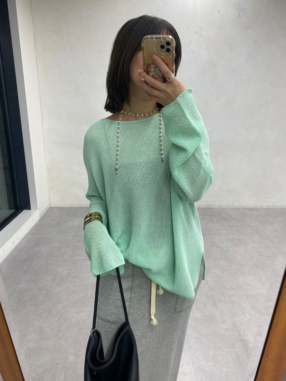 グリーン系のニット/セーター、グレー系のスカートを着用したレディースの春コーディネートの6枚目の写真