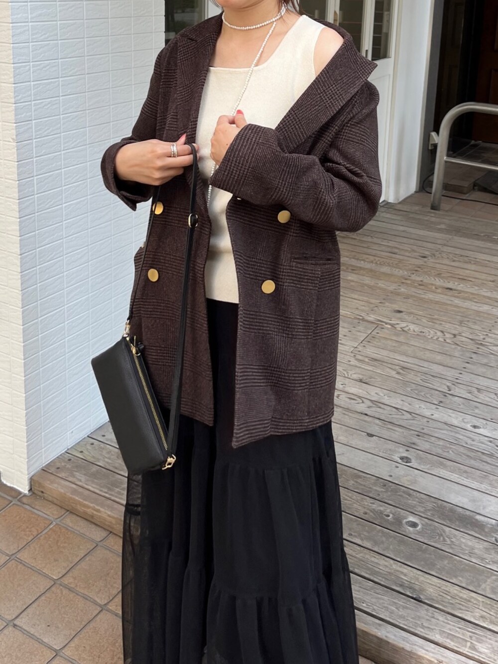 ブラウン系のテーラードジャケット、ブラック系のスカート、ブラック系のショルダーバッグを着用したレディースの秋コーディネートの2枚目の写真