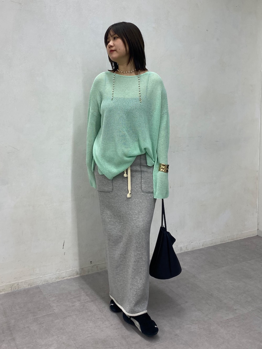 グリーン系のニット/セーター、グレー系のスカートを着用したレディースの春コーディネートの3枚目の写真
