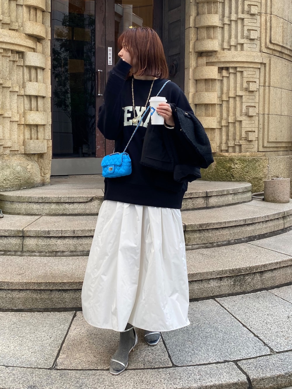 ブラック系のスウェット、ブラック系のノーカラージャケット、ホワイト系のスカートを着用したレディースの春コーディネートの3枚目の写真