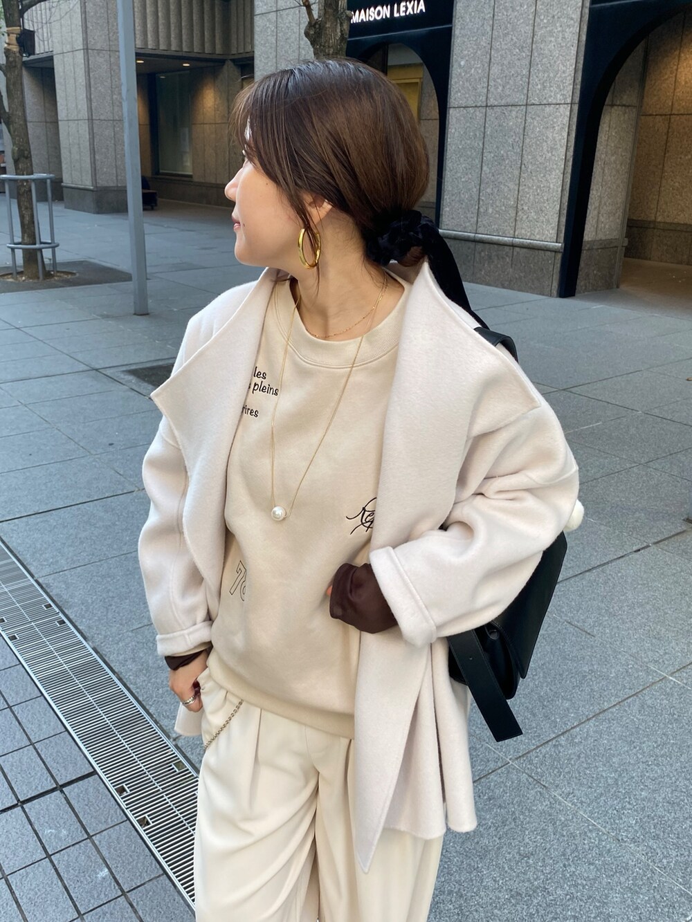 ホワイト系のその他アウター、ベージュ系のスラックス、ブラック系のショルダーバッグを着用したレディースの秋コーディネートの4枚目の写真