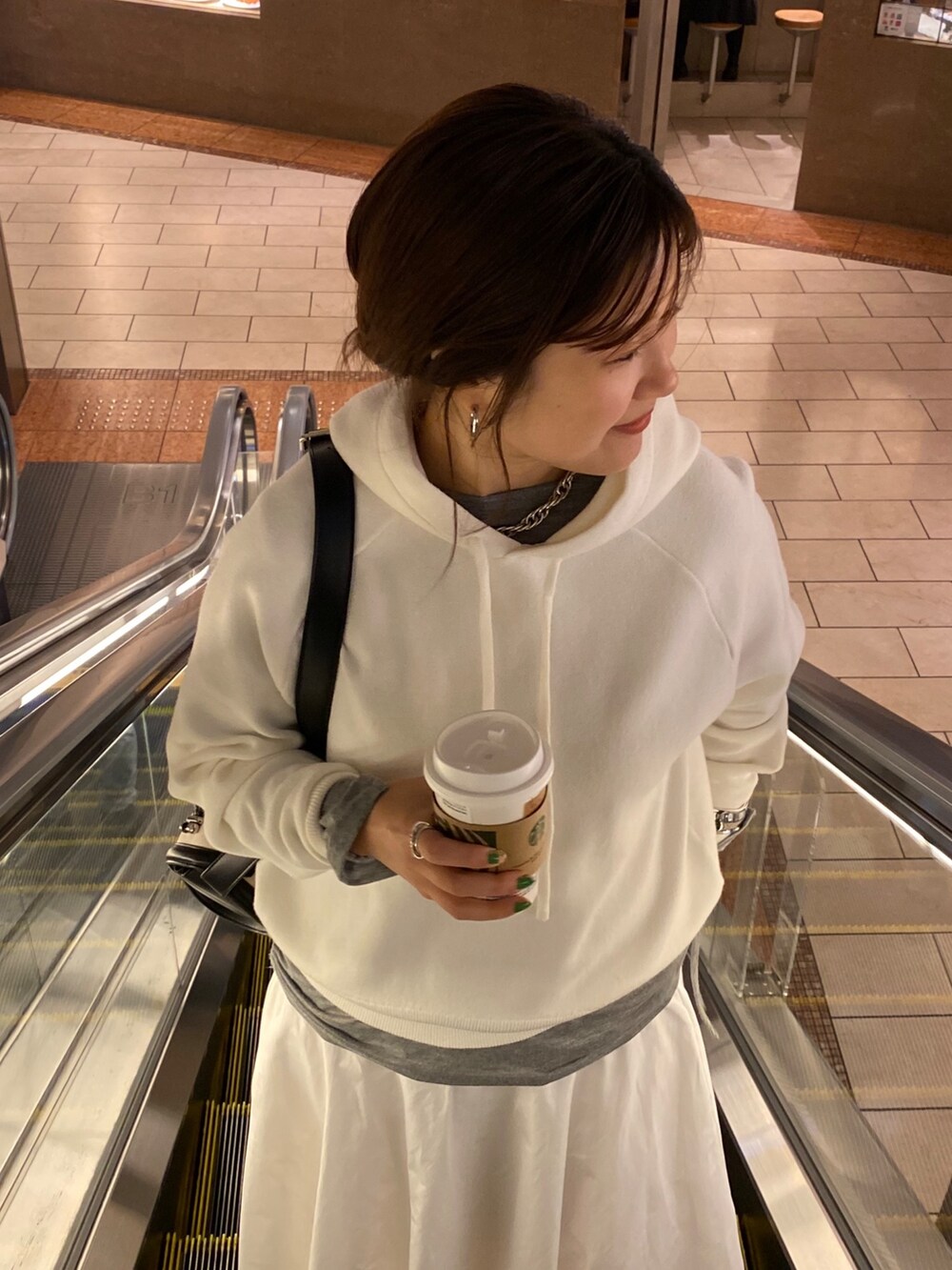 ホワイト系のスカート、ブラウン系のショルダーバッグ、グレー系のTシャツ/カットソーを着用したレディースの春コーディネートの6枚目の写真