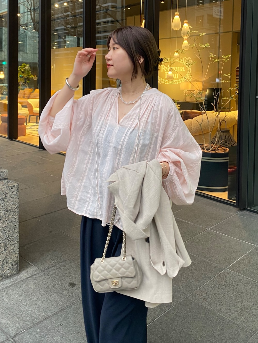 ピンク系のシャツ/ブラウス、ブルー系のスラックス、その他のネックレスを着用したレディースの春コーディネートの4枚目の写真