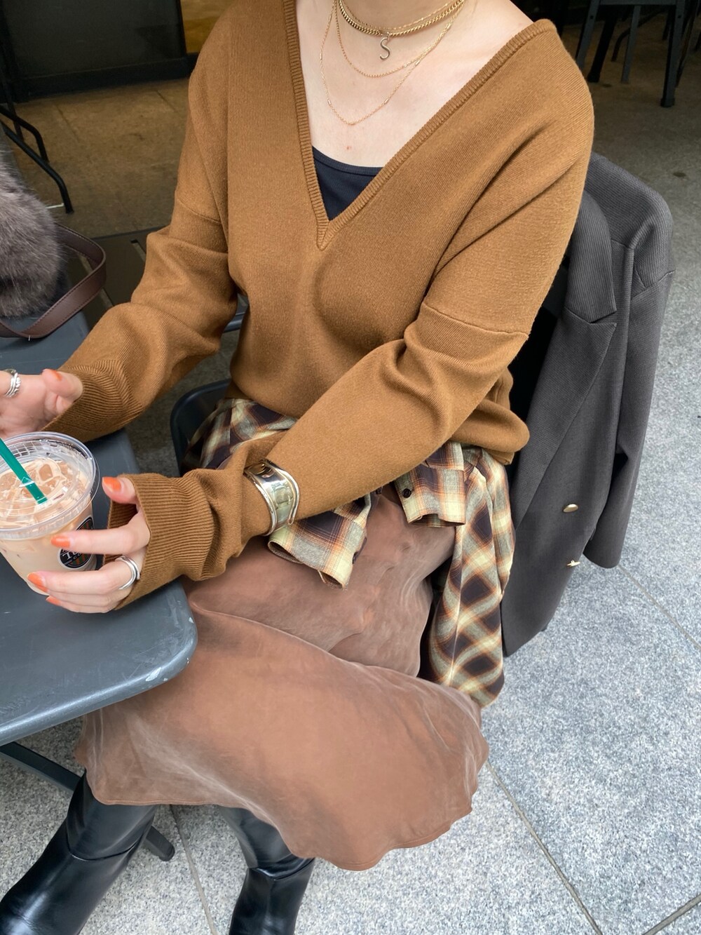 イエロー系のニット/セーター、ブラウン系のスカート、オレンジ系のシャツ/ブラウスを着用したレディースの冬コーディネートの2枚目の写真