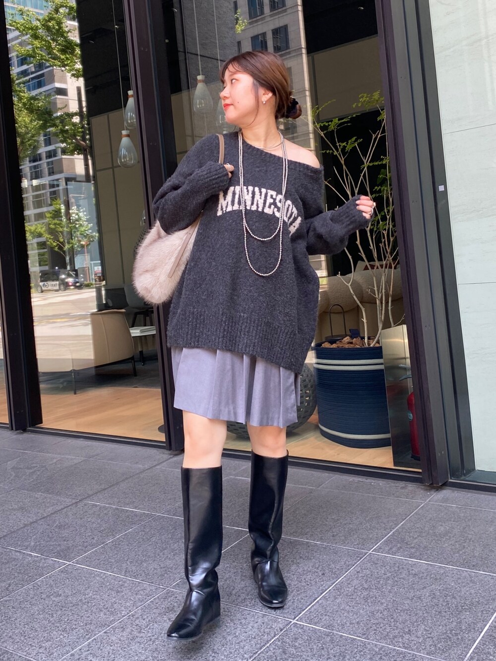 グレー系のニット/セーター、グレー系のスカート、ブラック系のブーツを着用したレディースの秋コーディネートの3枚目の写真