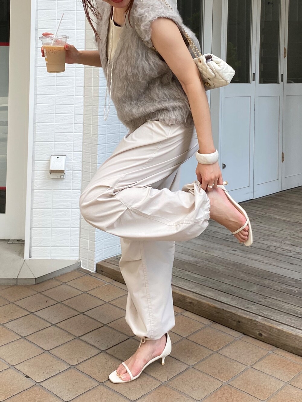 ベージュ系のベスト、ベージュ系のその他パンツ、ホワイト系のタンクトップを着用したレディースの秋コーディネートの3枚目の写真