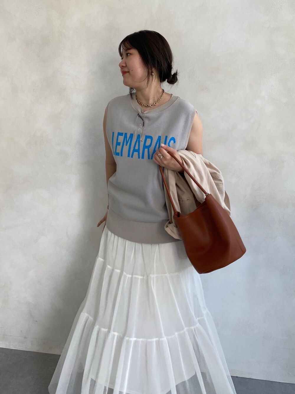 ベージュ系のテーラードジャケット、ホワイト系のスカート、ブラウン系のショルダーバッグを着用したレディースの夏コーディネートの5枚目の写真