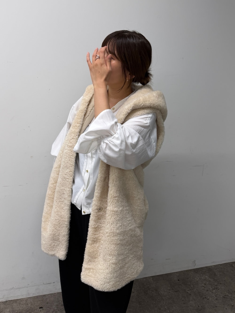 ホワイト系のシャツ/ブラウス、ホワイト系のベスト、ブラック系のスウェットパンツを着用したレディースの秋コーディネートの4枚目の写真