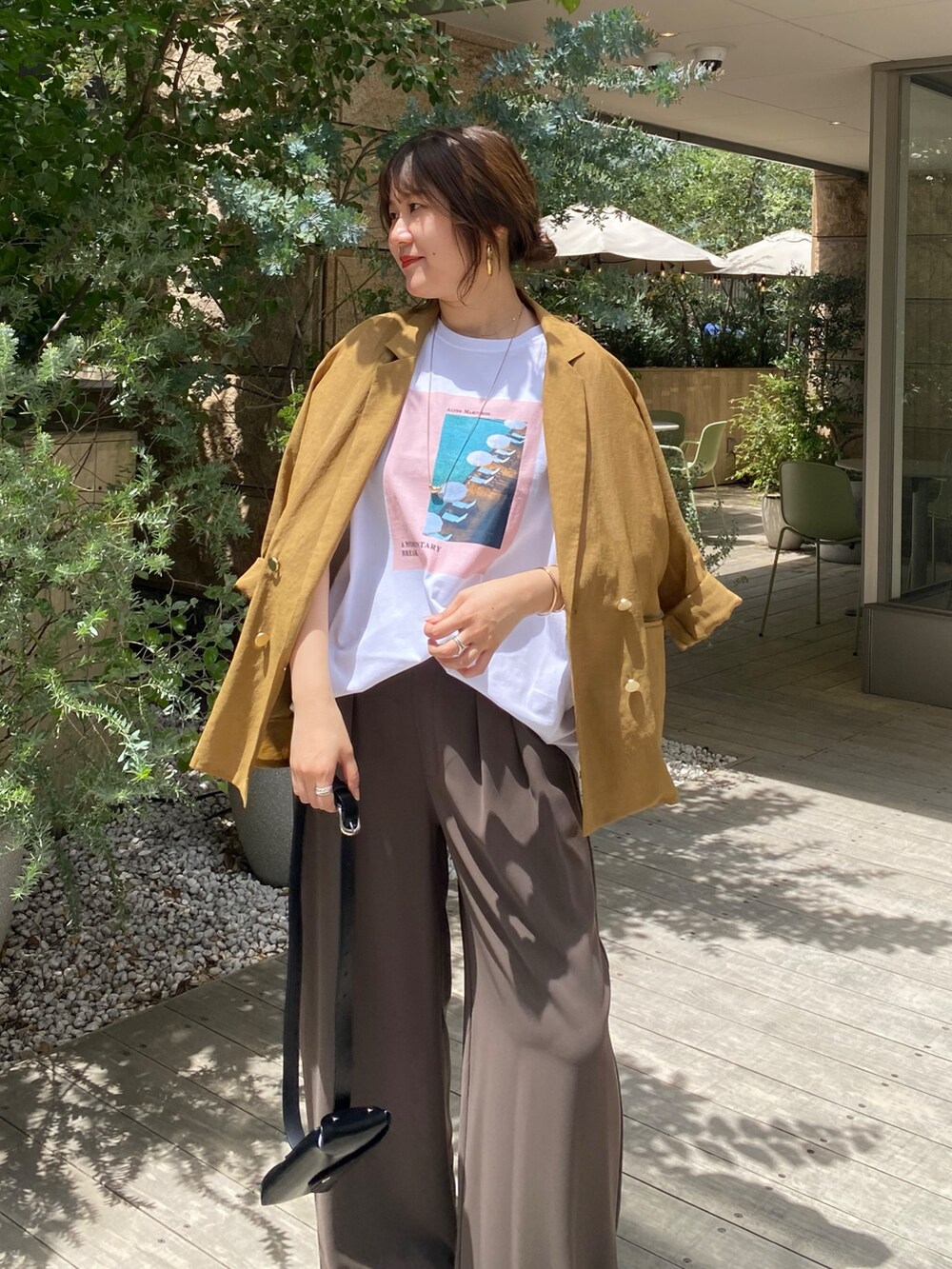 イエロー系のテーラードジャケット、ホワイト系のTシャツ/カットソー、ブラウン系のスラックスを着用したレディースの夏コーディネートの4枚目の写真