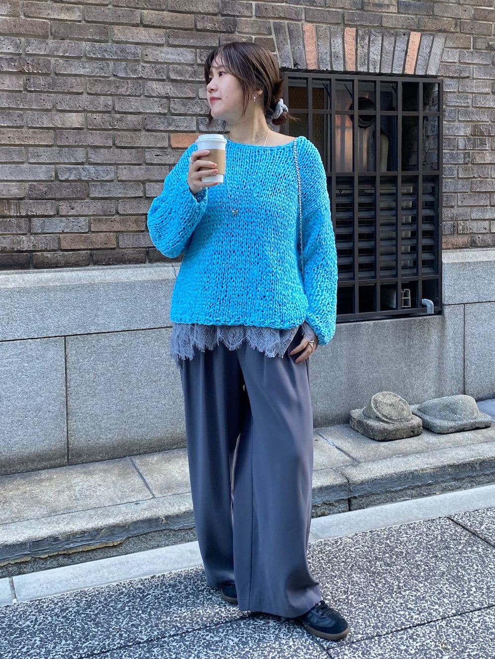 ブルー系のニット/セーター、グレー系のTシャツ/カットソー、グレー系のスラックスを着用したレディースの冬コーディネートの5枚目の写真