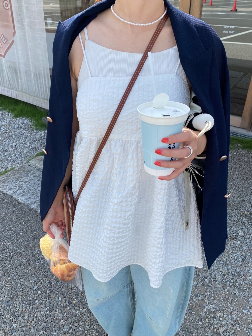 ブルー系のテーラードジャケット、ホワイト系のキャミソール、ブルー系のデニムパンツを着用したレディースの夏コーディネートの6枚目の写真