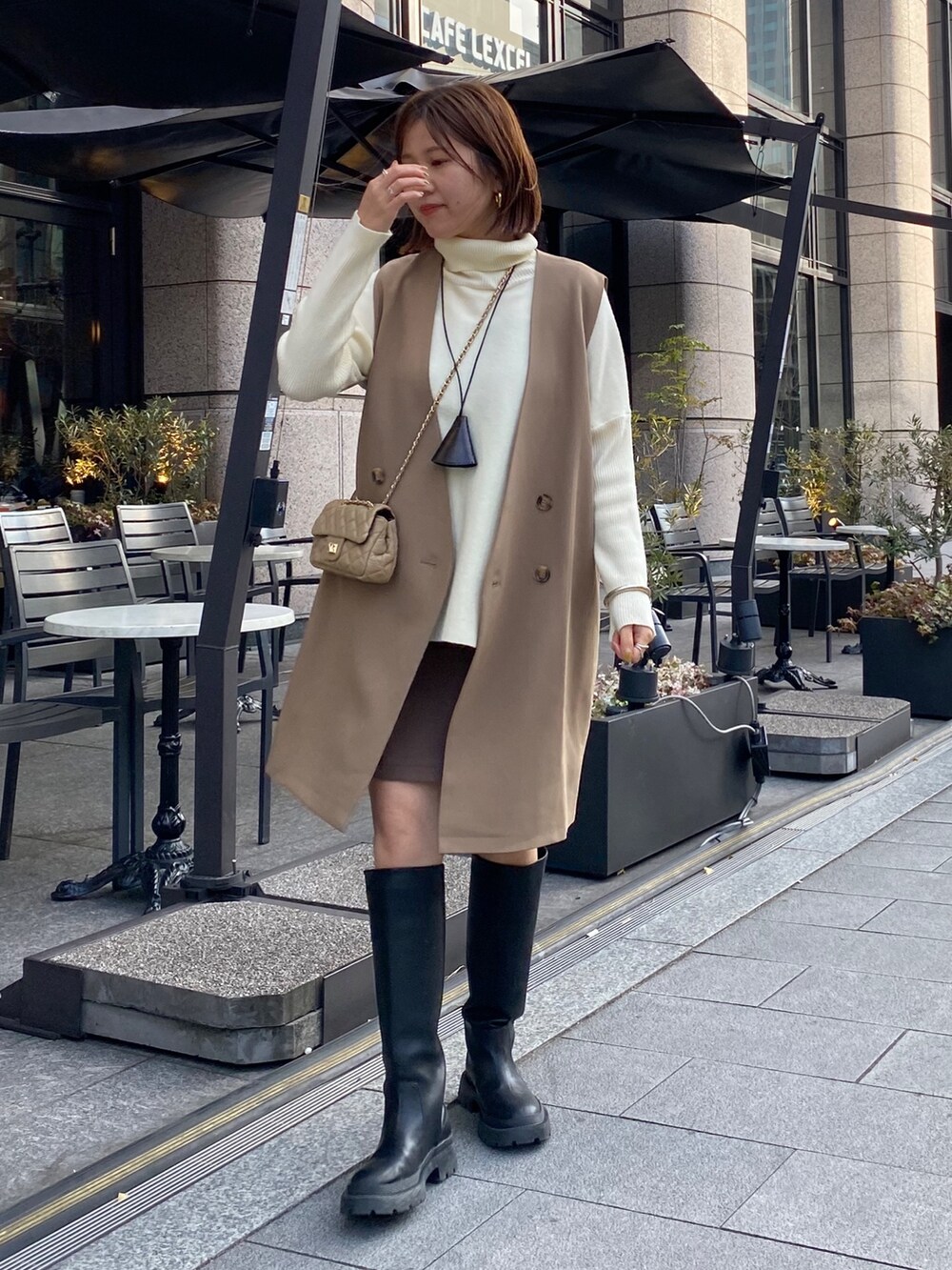 イエロー系のベスト、ホワイト系のニット/セーター、ブラウン系のスカートを着用したレディースの冬コーディネートの4枚目の写真